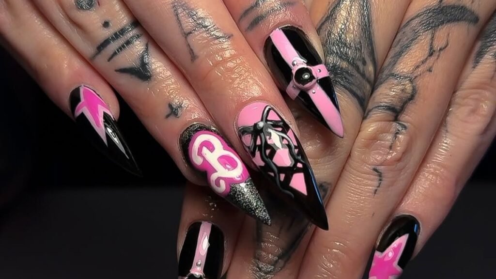 Stiletto nails split between glossy black and hot pink, with a glittery Barbie script, bow, and harness detail
