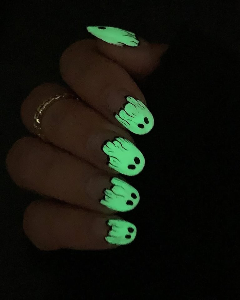 Glow Ghosts Halloween Nail Ideas glowing bright green in the dark, with simple wide-eyed cartoon ghost faces on each tip