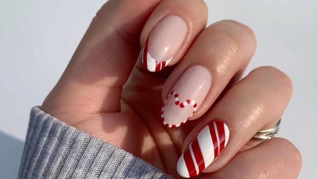 Nude nails with red and white candy cane stripe accents and a red dot heart design