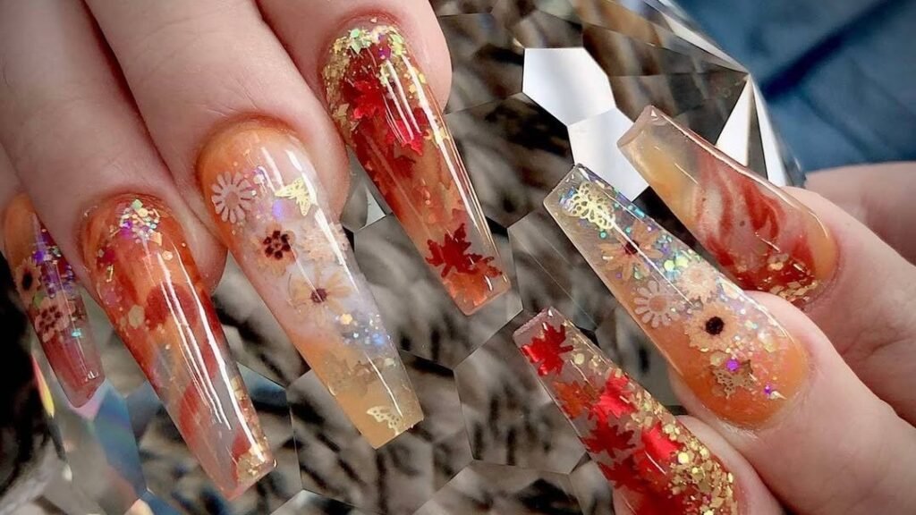 Glitter Thanksgiving nail art with red maple leaf details and gold glitter on long coffin nails