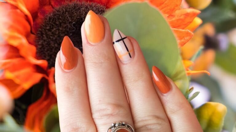Orange fall nail polish with a graphic linear accent nail against a sunflower
