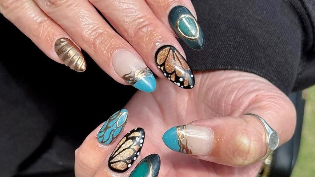 Gold chrome and teal cat-eye Thanksgiving nails with metallic butterfly wing art on almond-shaped nails