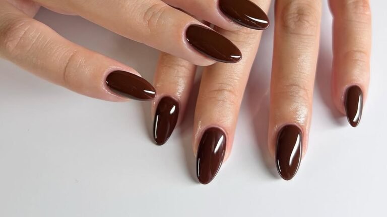 Glossy deep chocolate brown nail polish on almond-shaped nails, ten fingers fanned out showing a solid mocha manicure Thanksgiving nail idea