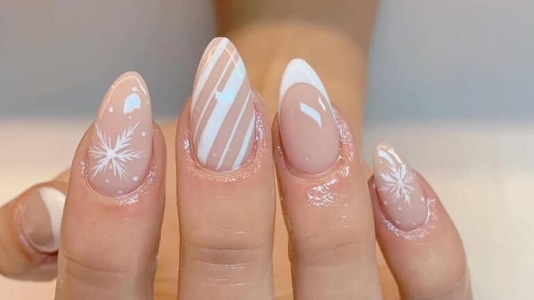 Nude manicure with two white snowflake accent nails and a candy stripe accent nail