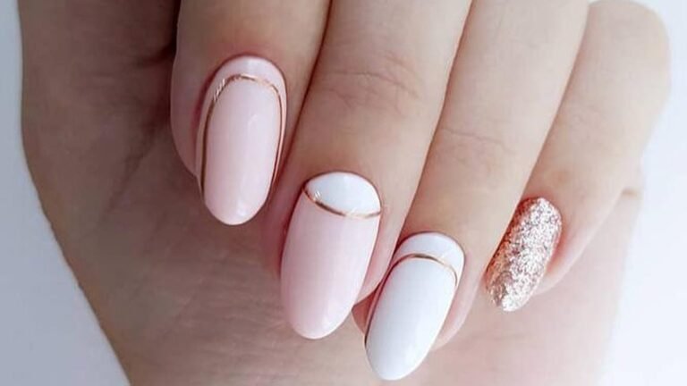Minimalist almond nails in soft blush pink and milky white with thin gold lines curving across three nails and one rose gold glitter accent nail on the pinky, shown on a relaxed hand against a pale background.