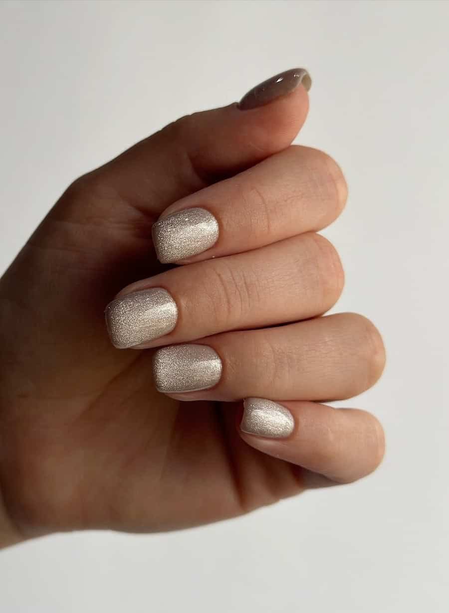 Sparkling champagne-colored manicure on hand