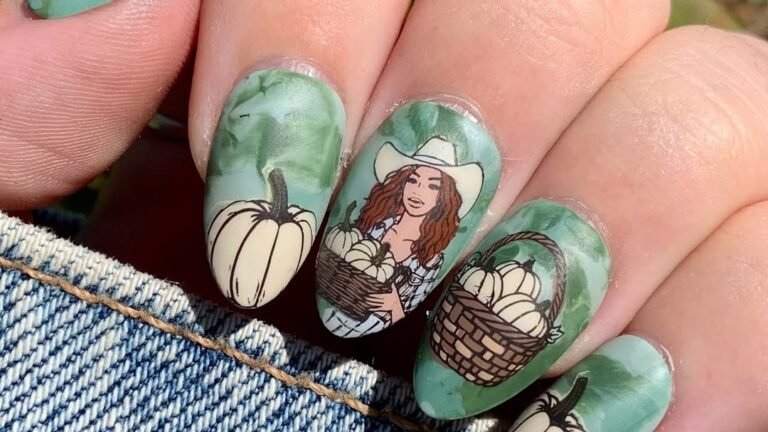 A hand holding up nails painted with an illustrated cowgirl in a white hat, a wicker basket of pale pumpkins, and a single cream pumpkin against a green watercolor background, with denim visible below