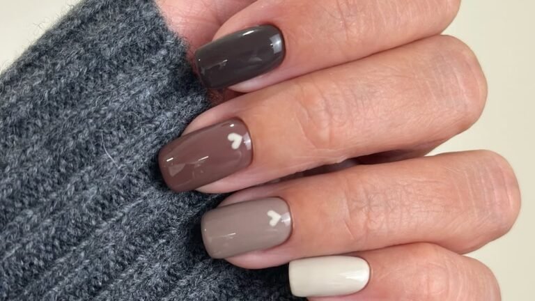 Beige neutral manicure with a tonal mix of dark brown, mocha, taupe, and cream nails, one with a small white heart detail