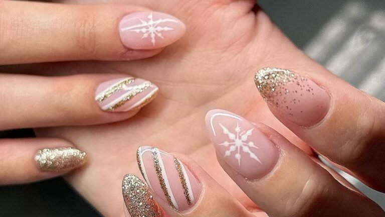 Nude pink almond nails with gold glitter accents, white snowflake nail art, and glitter striped tips for a holiday manicure