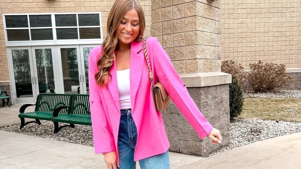 Woman smiling in an oversized hot pink blazer over a white tank top and denim jeans, one of 12 casual February outfit ideas