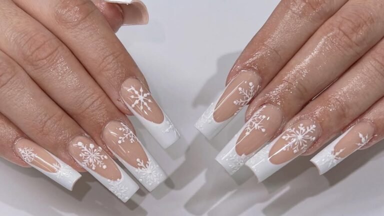 Long white French tip acrylic nails with hand painted white snowflake nail art on a nude base, both hands shown