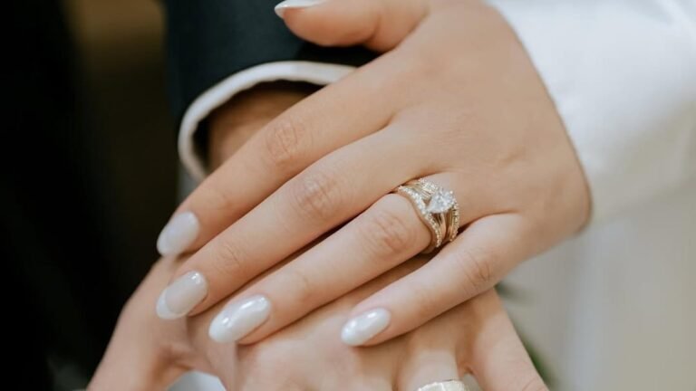 Bride and groom holding hands showing sheer milky white wedding manicure and rings