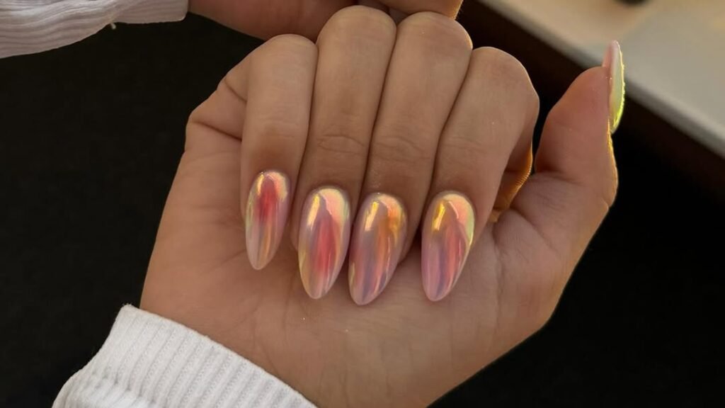 Almond nails with an iridescent chrome finish shifting between peach, rose, and gold