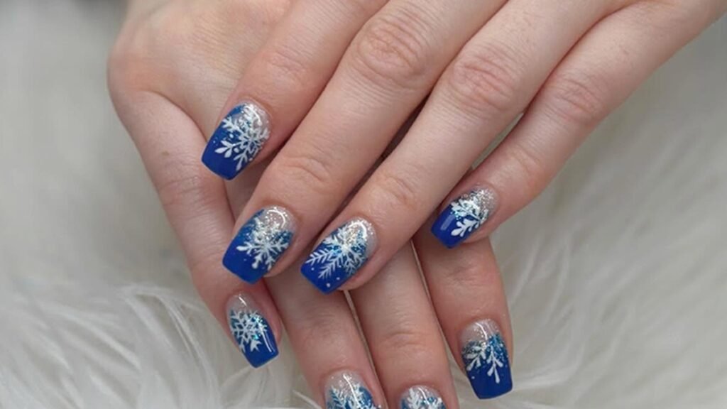 Cobalt blue winter manicure with hand-painted white snowflake nail art on glossy square nails