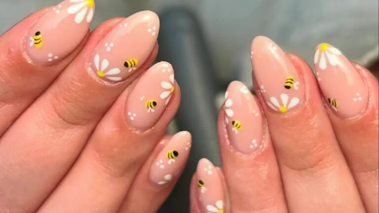 Bee and daisy nail art on short round nails, with tiny bumblebees and white daisies painted on a soft pink base