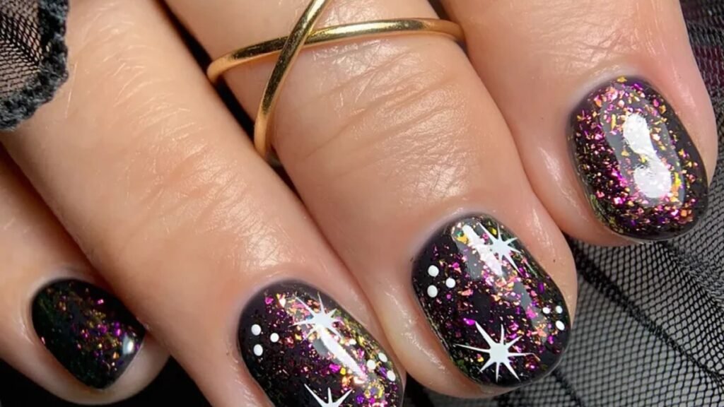 Black manicure with metallic flake polish and white star accents