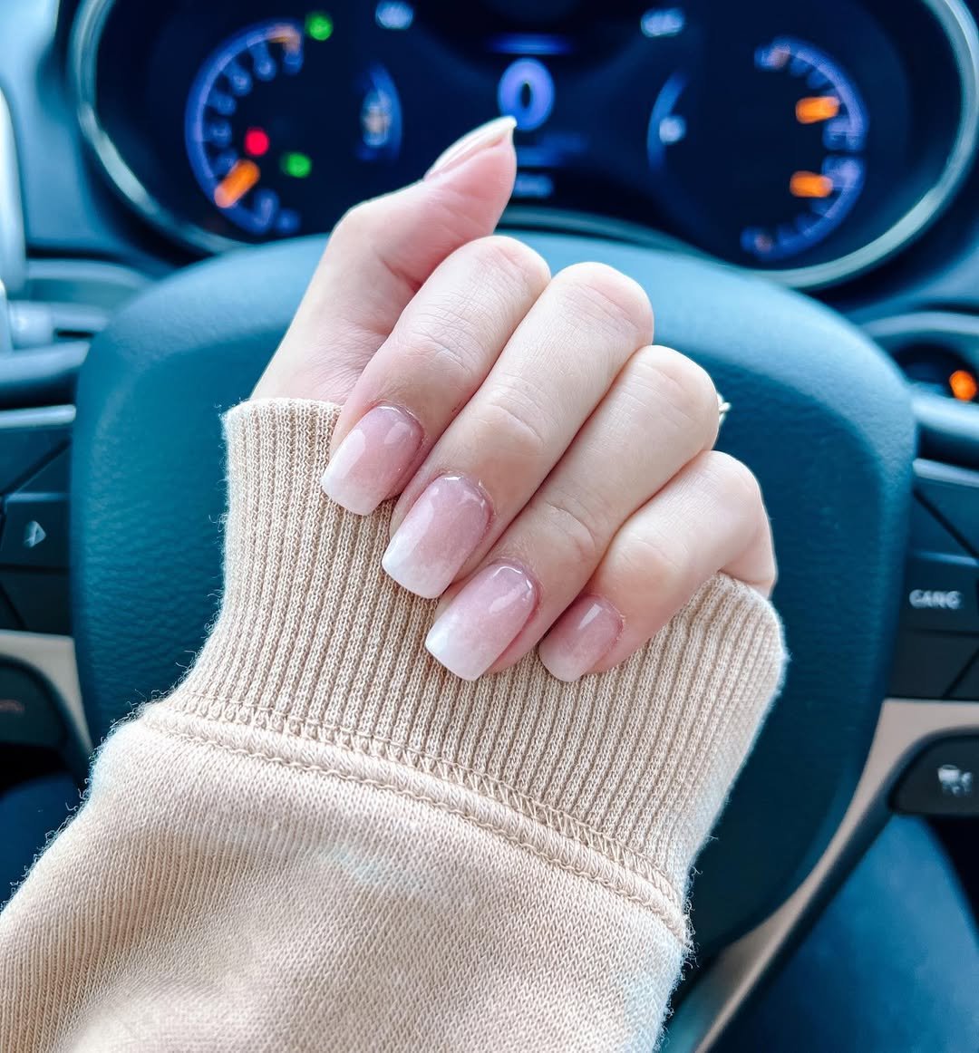 Hand with manicured nails on steering wheel