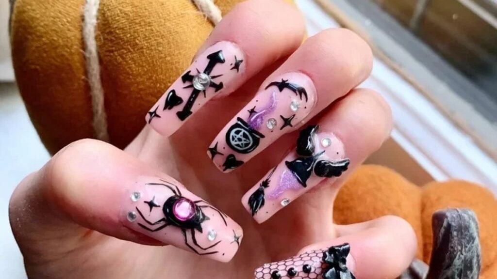Hot pink and black nail art with skull, snake, and flame designs on stiletto-shaped nails