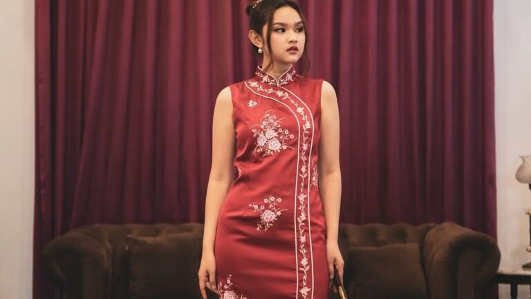 Woman in a classic red modern qipao dress with floral embroidery and side slit, a Chinese New Year dress idea