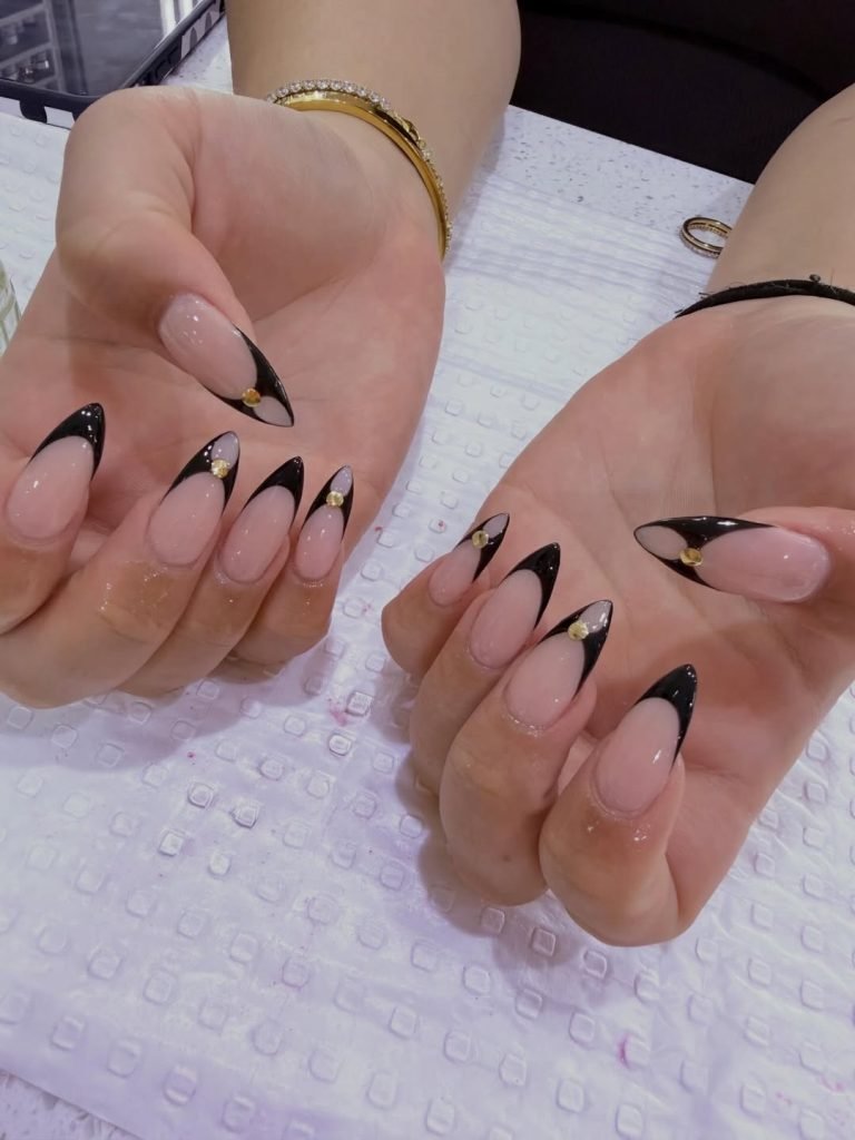 Elegant black-tipped manicure with embellishments.