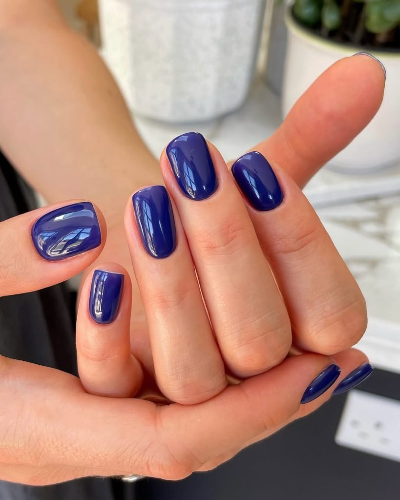 Elegant dark blue manicure on hands.