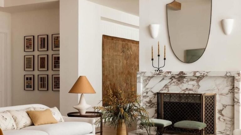 Living room with wood beam ceiling, marble fireplace, and mixed wood, boucle, and woven textures in warm earth tones