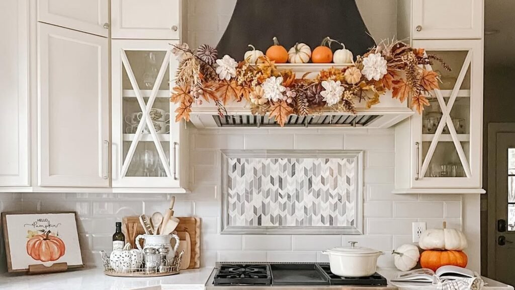 Fall kitchen decor with pumpkin and floral garland draped over a black range hood, white cabinets, and a plaid runner on the floor