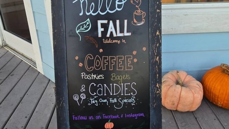 Hand-lettered fall chalkboard sign advertising coffee, pastries, bagels, and fall specials, decorated with a small pumpkin doodle
