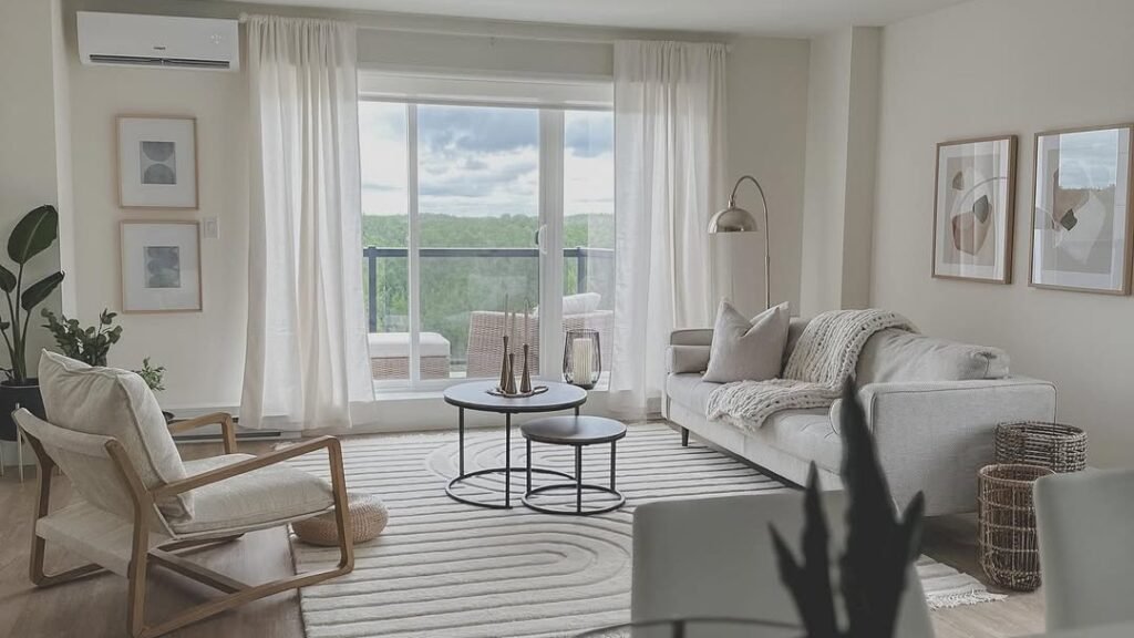 Bright neutral living room with an accent chair, sofa, and layered rugs, styled with no built-in furniture or permanent fixtures