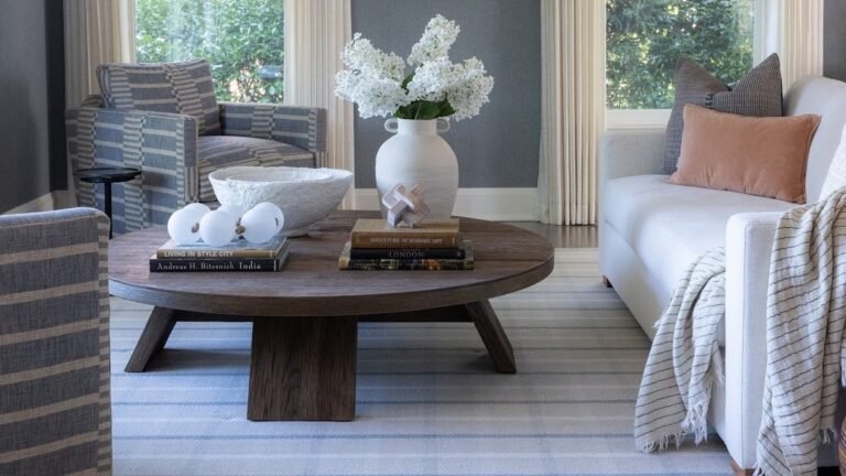 Oversized blue and white striped swivel chair anchoring a bright living room with a curved sofa and round wood coffee table