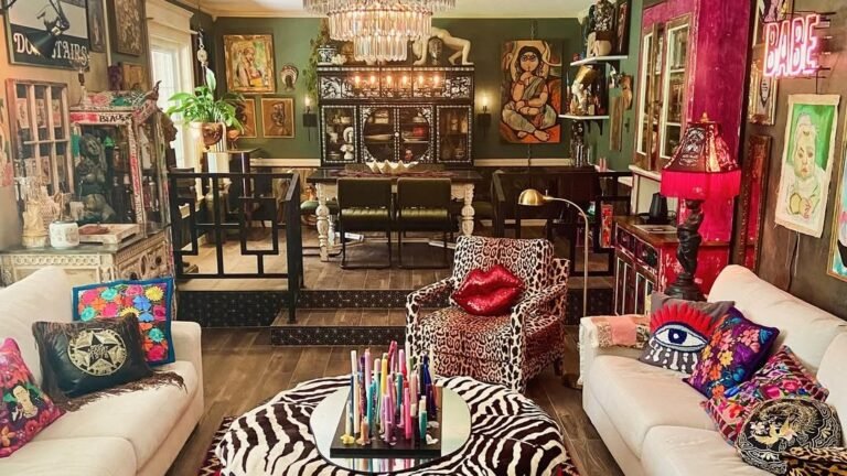 Bohemian maximalist living room with a red patterned rug, leopard print armchair, zebra ottoman, crystal chandelier, and gallery wall of colorful art