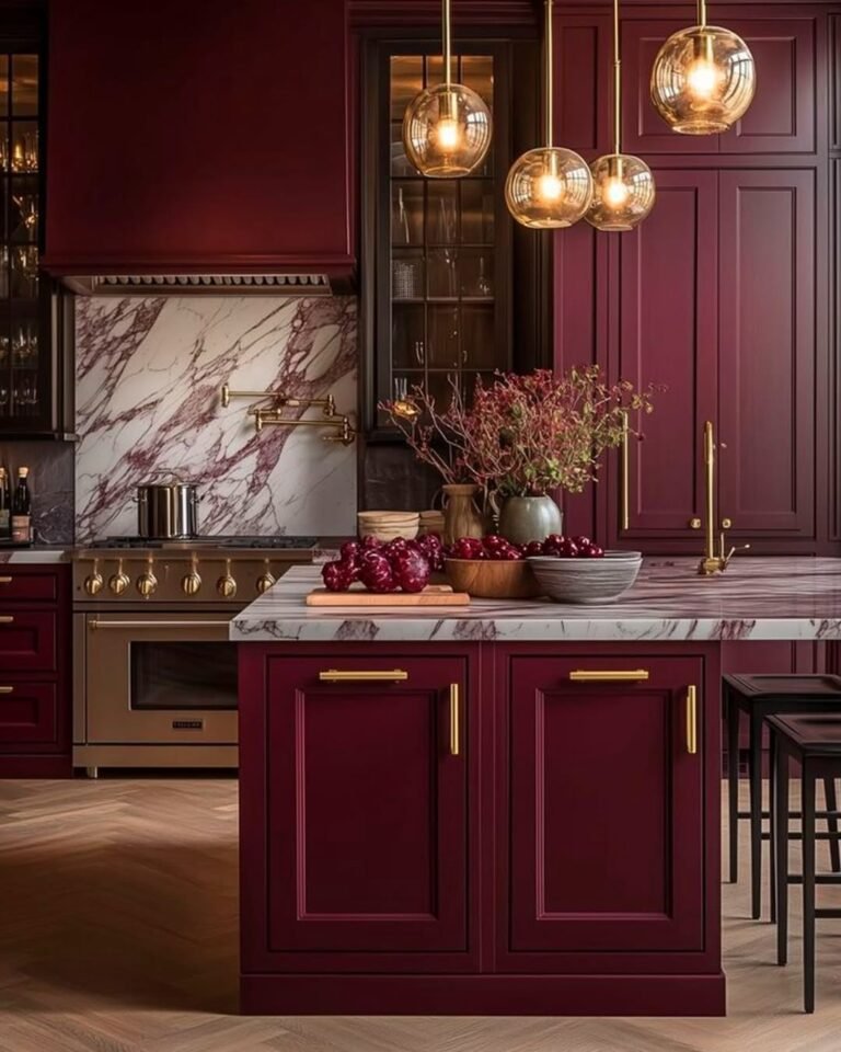 Burgundy kitchen island with marble countertop and backsplash, brass pendant lights, and a pot filler faucet