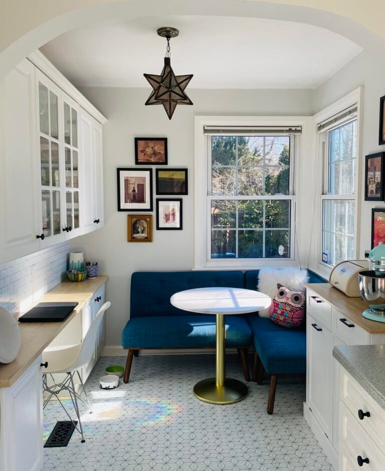 Cobalt blue built-in banquette bench fitted into a kitchen corner, with a round marble table on a brass pedestal and a star pendant light overhead