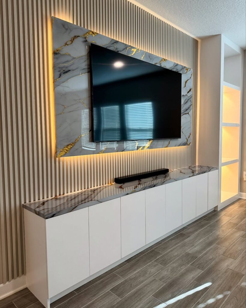 Marble and gold veined accent wall with backlit LED trim behind a wall mounted TV, paired with a minimal white floating cabinet