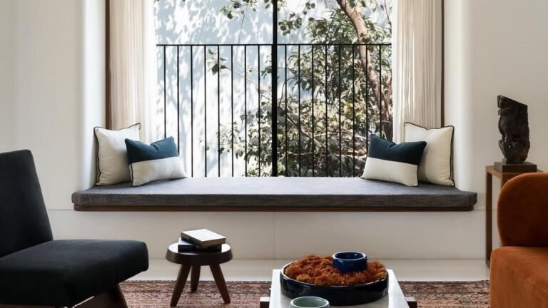 Minimalist living room window seat with a floating ledge design, black-framed window, and neutral throw pillows