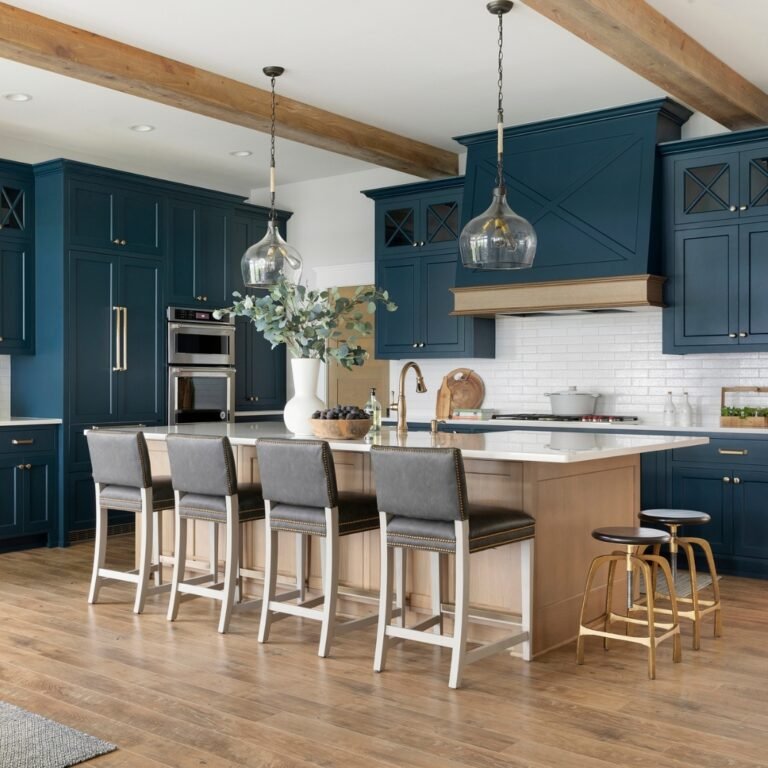 Navy blue kitchen cabinets paired with warm oak wood beams, a light wood island base, and brass pendant lights to keep the space bright and warm