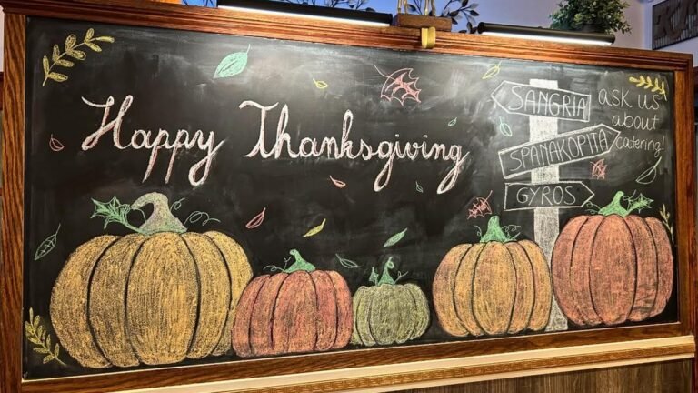 Hand-lettered black chalkboard reading 'Happy Thanksgiving' above a row of five colorful chalk-drawn pumpkins in gold, rust, and sage, framed in dark wood