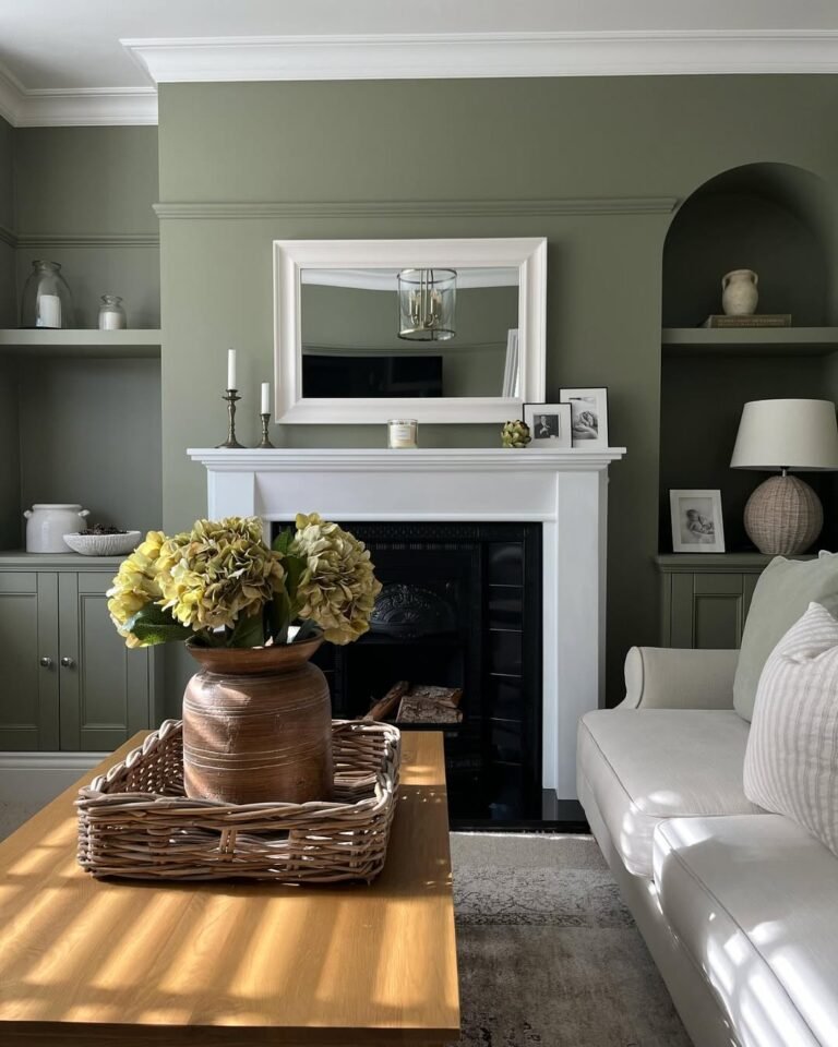 Living room with sage green walls, a white mantel, and a black cast-iron fireplace styled with yellow hydrangeas and brass candlesticks