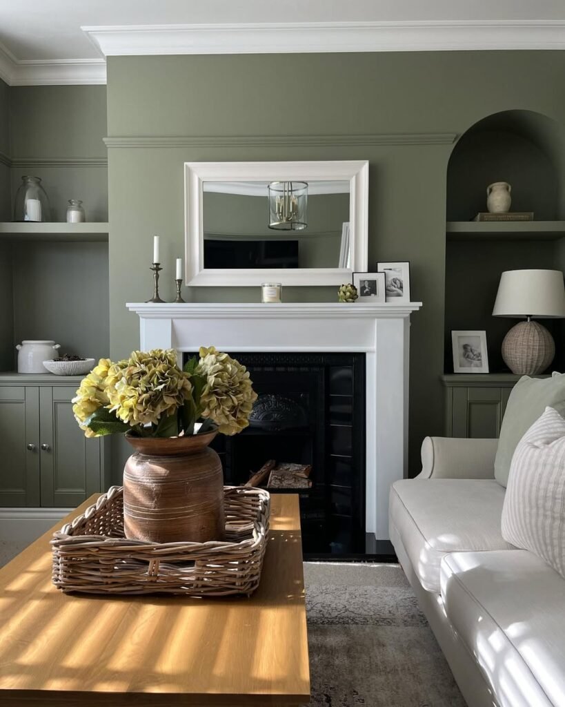 Living room with sage green walls, a white mantel, and a black cast-iron fireplace styled with yellow hydrangeas and brass candlesticks