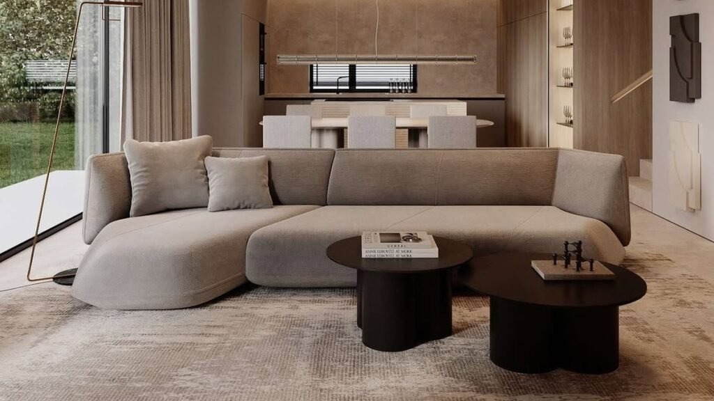Curved beige sculptural sofa with two round wood coffee tables in a minimalist living room with no patterned decor