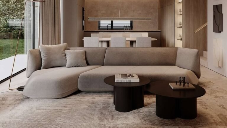 Curved beige sculptural sofa with two round wood coffee tables in a minimalist living room with no patterned decor