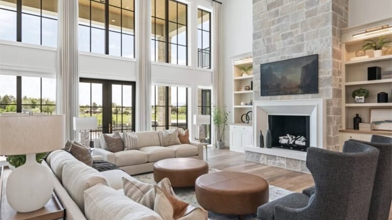 Open concept living room with a two-story stone fireplace, built-in shelving, and a beamed ceiling