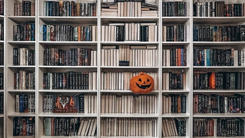 Single carved pumpkin centered on a white bookshelf wall, styled as Halloween bookshelf decor