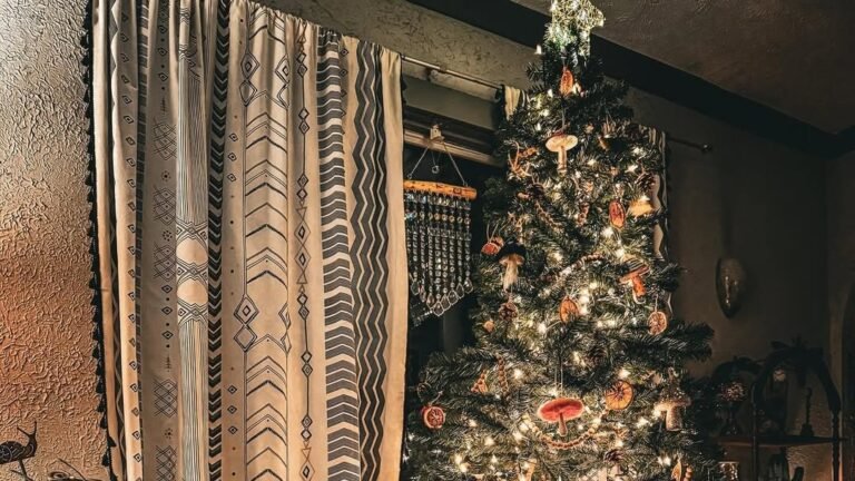 Christmas tree decorated with dried orange slice ornaments, wood mushrooms, and warm string lights in a dark boho living room