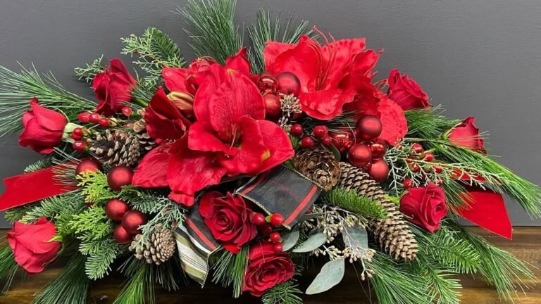Red amaryllis and rose Christmas centerpiece with pinecones and pine greenery on a wood table
