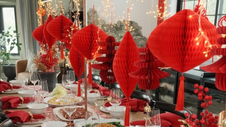 Overlapping red paper fans in mixed sizes form a large cluster on a light gray wall, with gold cutouts in a few of the centers and red blossom sprigs tucked between the fans.